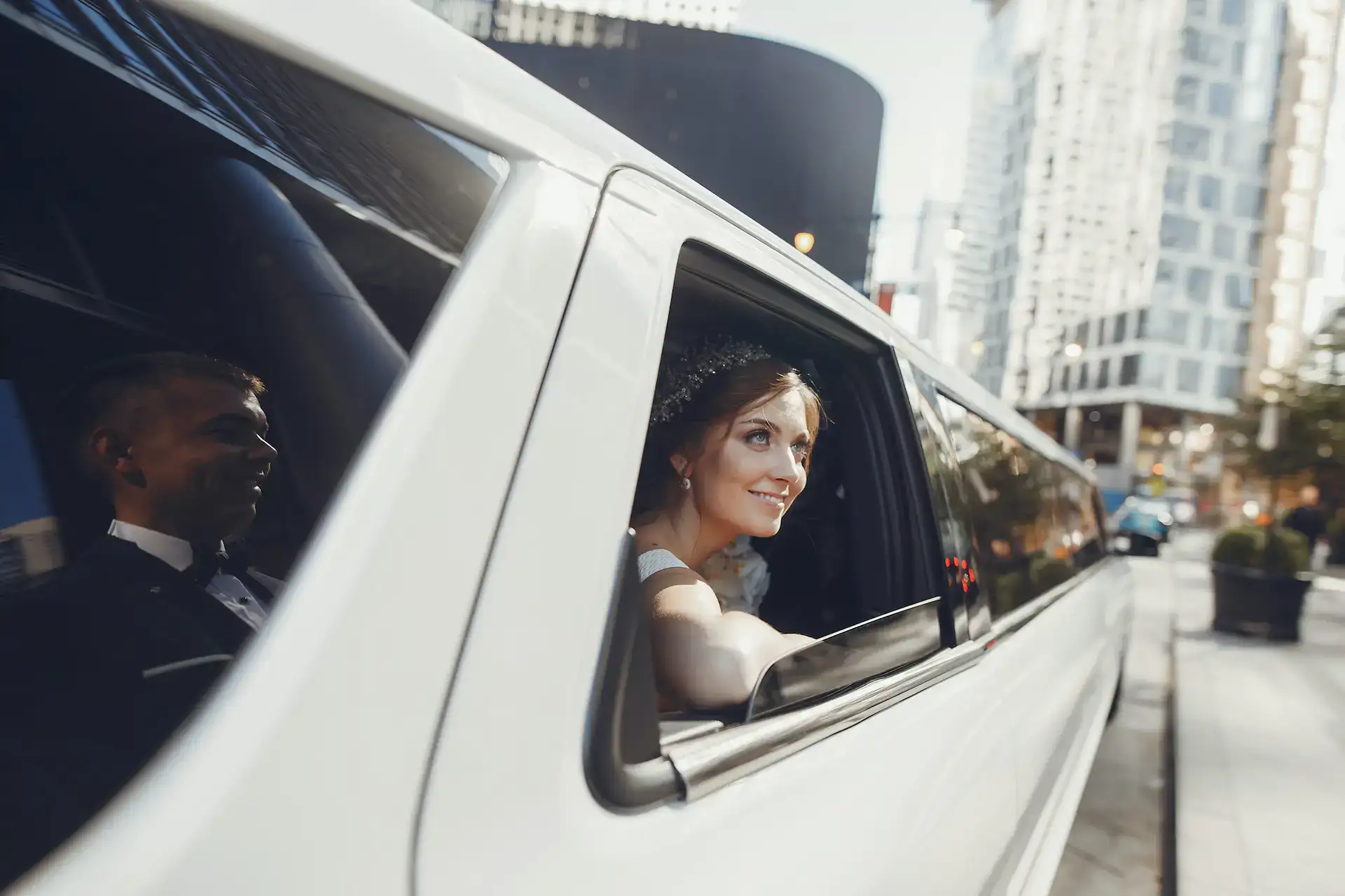 A person in formal attire looks out the window of a white limousine, set against the backdrop of tall buildings and city streets. This elegant moment reflects the special occasion atmosphere often experienced in Atlantic City, NJ.